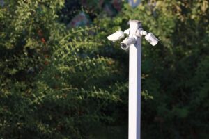 A modern dual lens outdoor security camera mounted on a clean home wall.